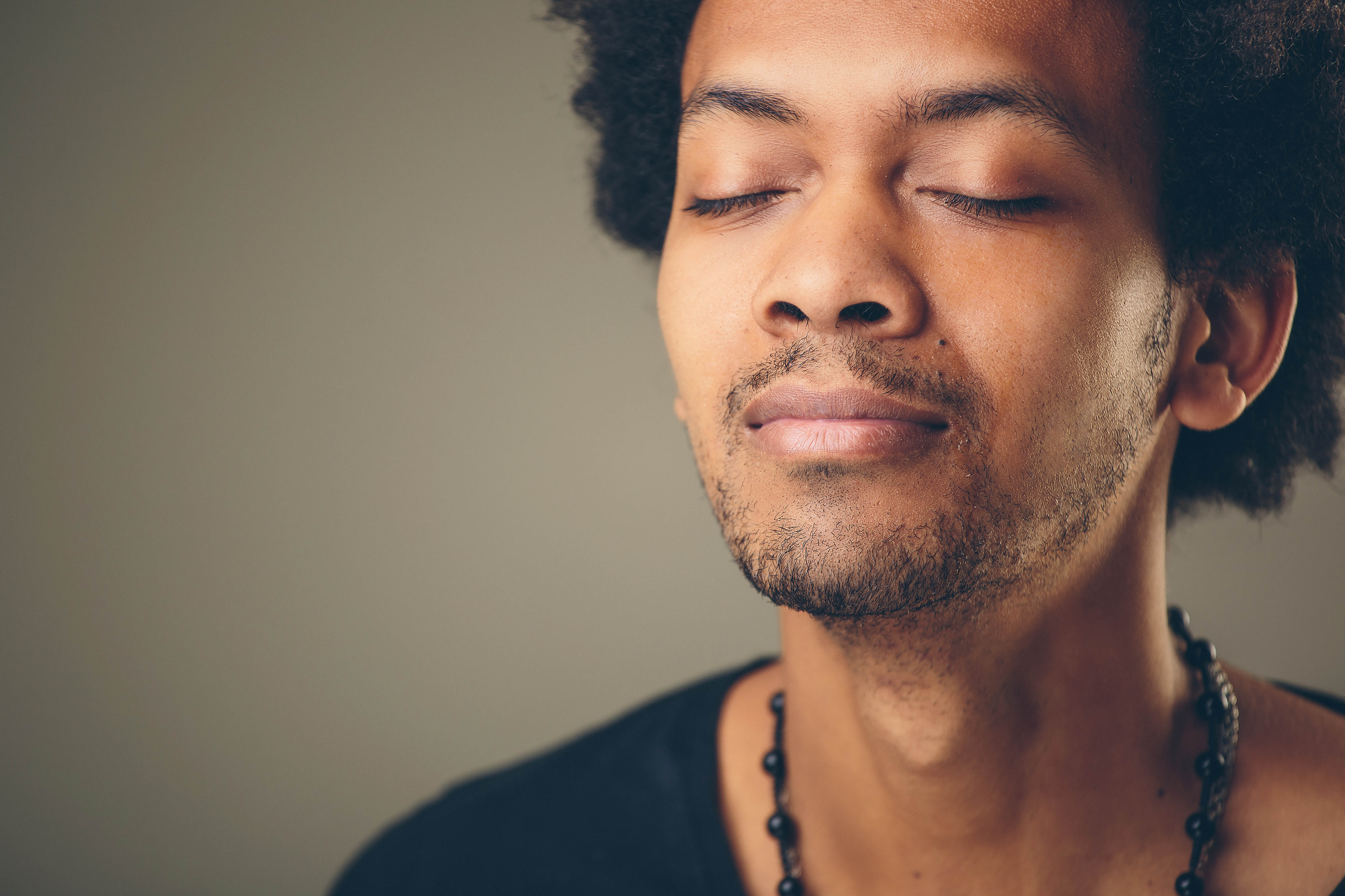 Close-up of young black man with his eyes closed, breathing in deeply.  Close-up of young black man with his eyes closed, breathing in deeply.